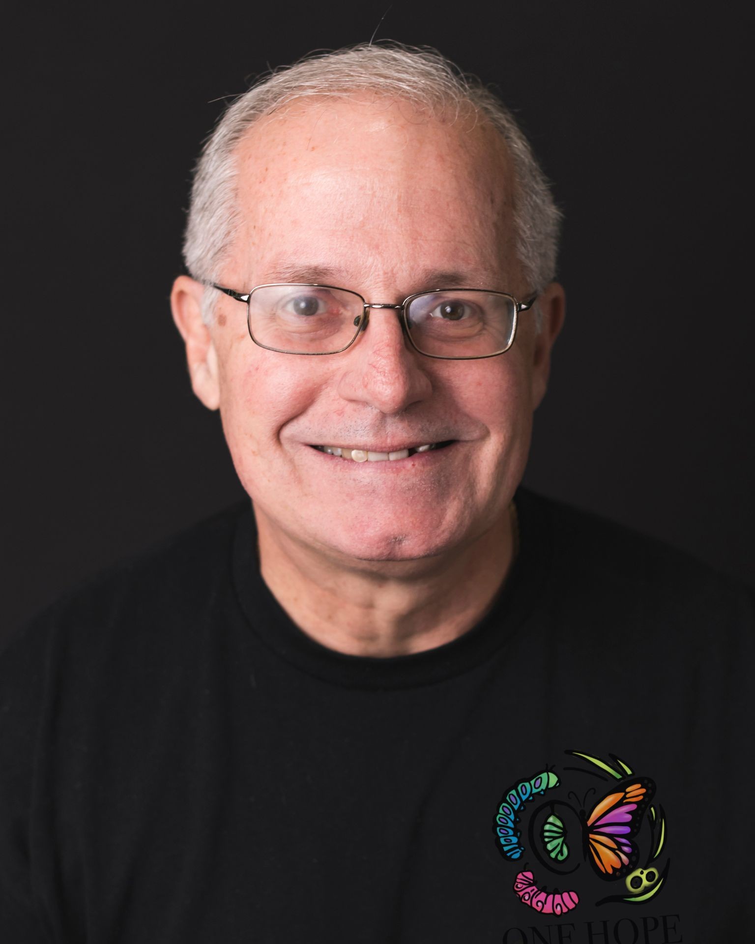 Person wearing a black shirt with a colorful butterfly and the text 'One Hope' on it.