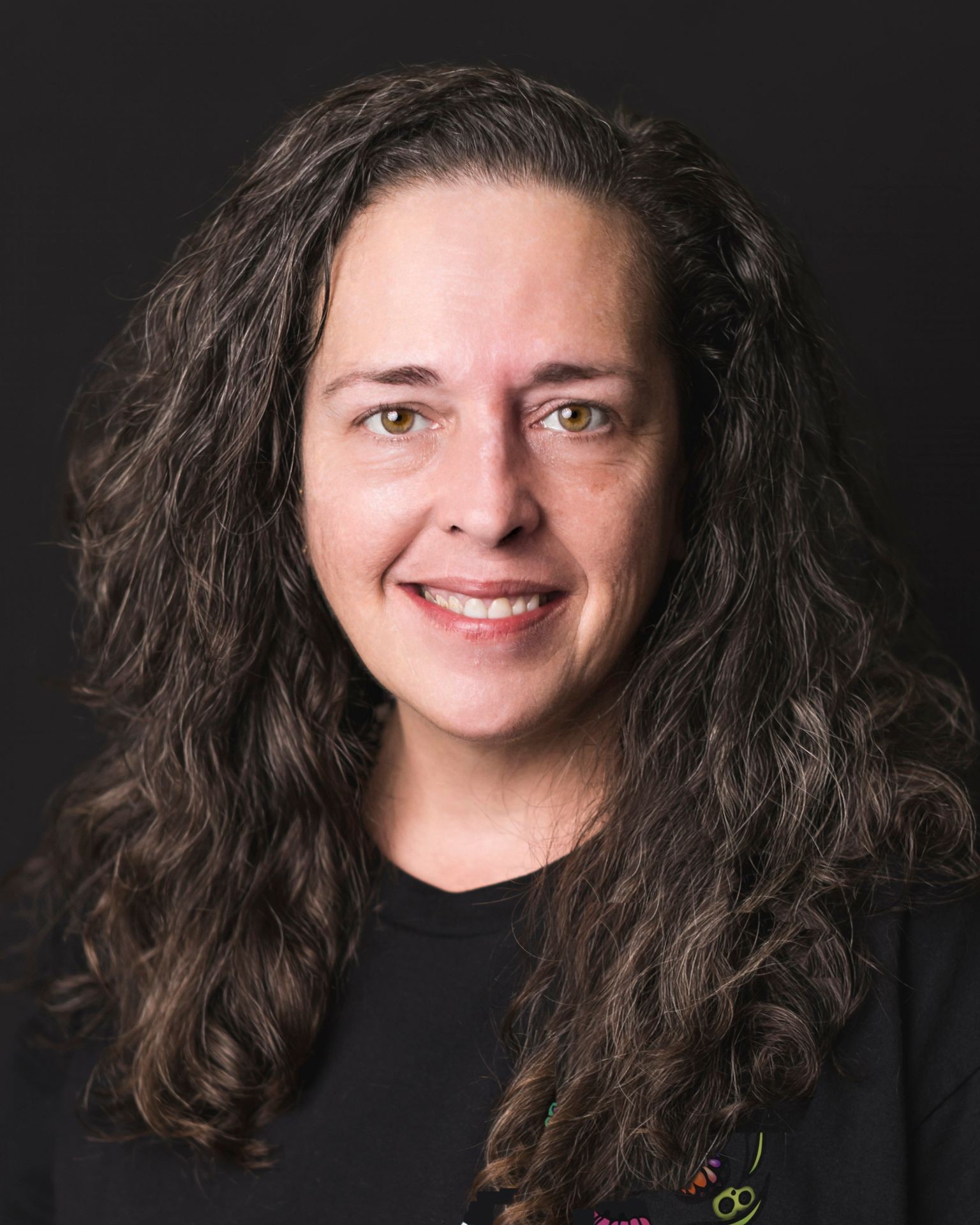 Person with long, curly hair wearing a black shirt.