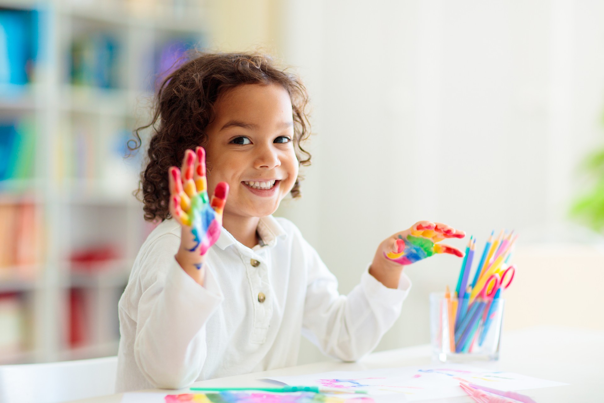 Child drawing rainbow. Paint on hands.