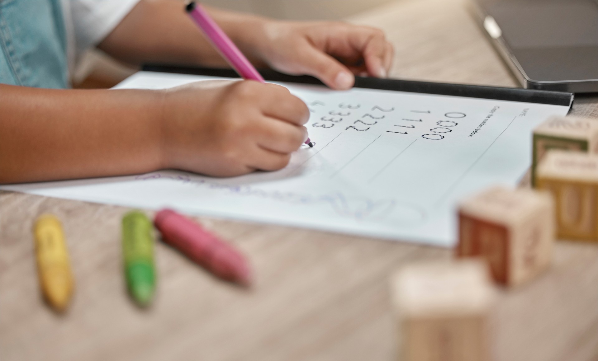 Education, paper and hands of child writing math homework, learning and study numbers for youth child development. Table, pen and young school student studying mathematics in kindergarten classroom